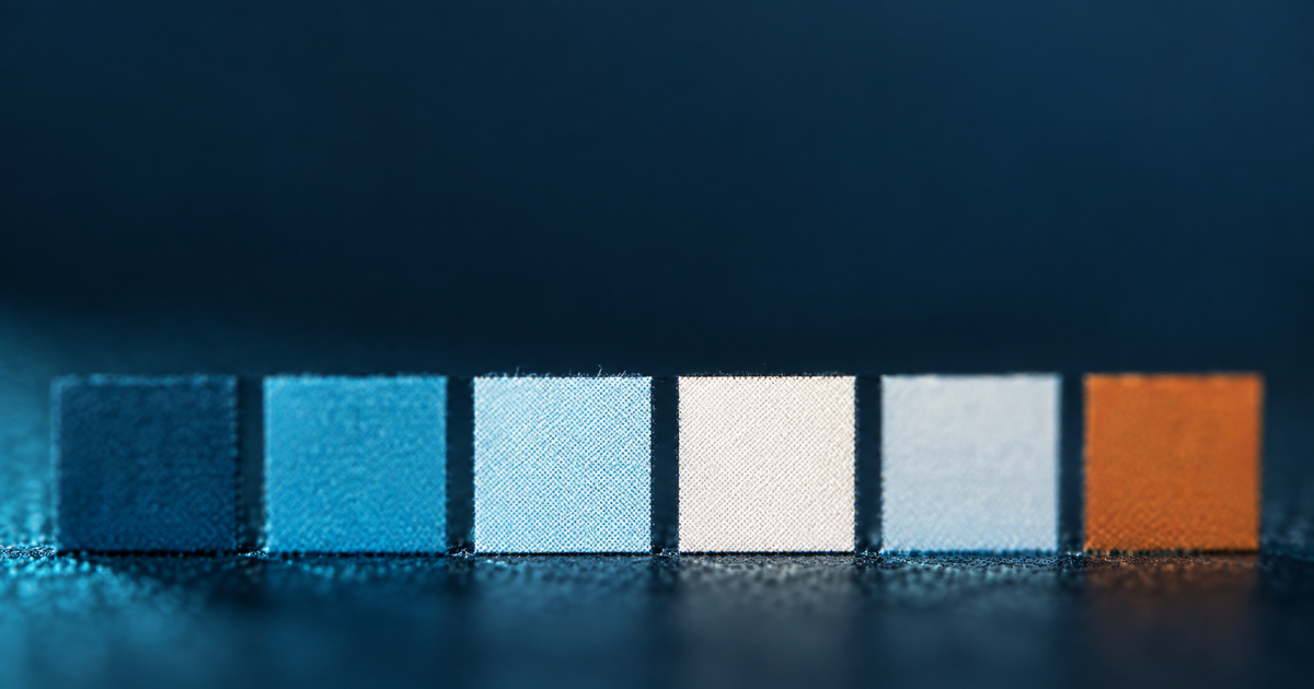 Macro of colour checker patches under raking teal light, five reading as a consistent sequence and the sixth amber and out of sequence